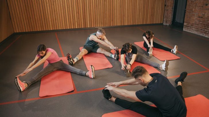 Adults in a yoga studio stretch on mats, promoting fitness and flexibility.
